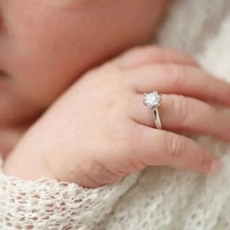 Close-up of a newborn's hand wearing an exquisite angel ring, perfect for ages 0-6 months, unisex design.