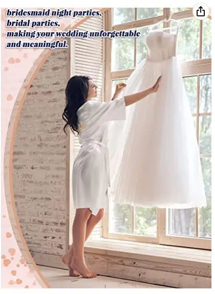 Woman in a white robe admiring a bridal gown by a window, perfect for bridesmaid and bridal parties.