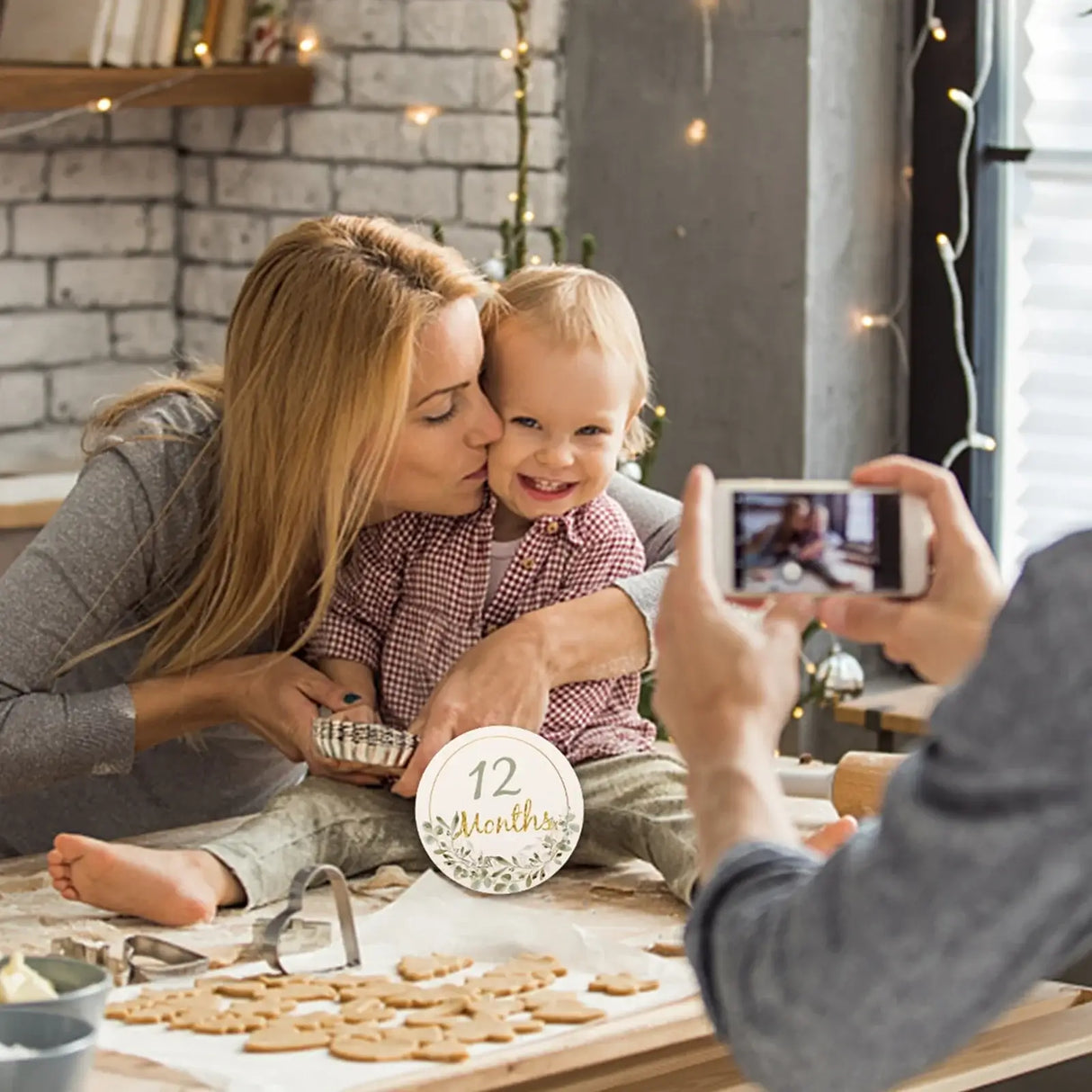 Mom and baby celebrating 12 months with milestone card, capturing memories during a baking session.