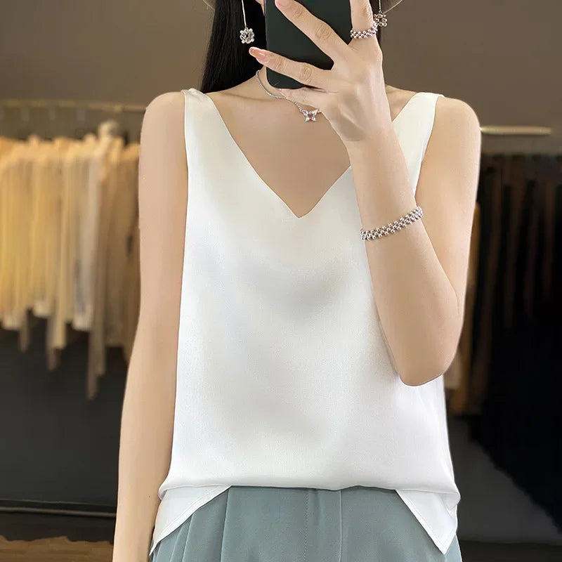 Woman wearing a white satin V-neck camisole top, showcasing summer style and comfort.