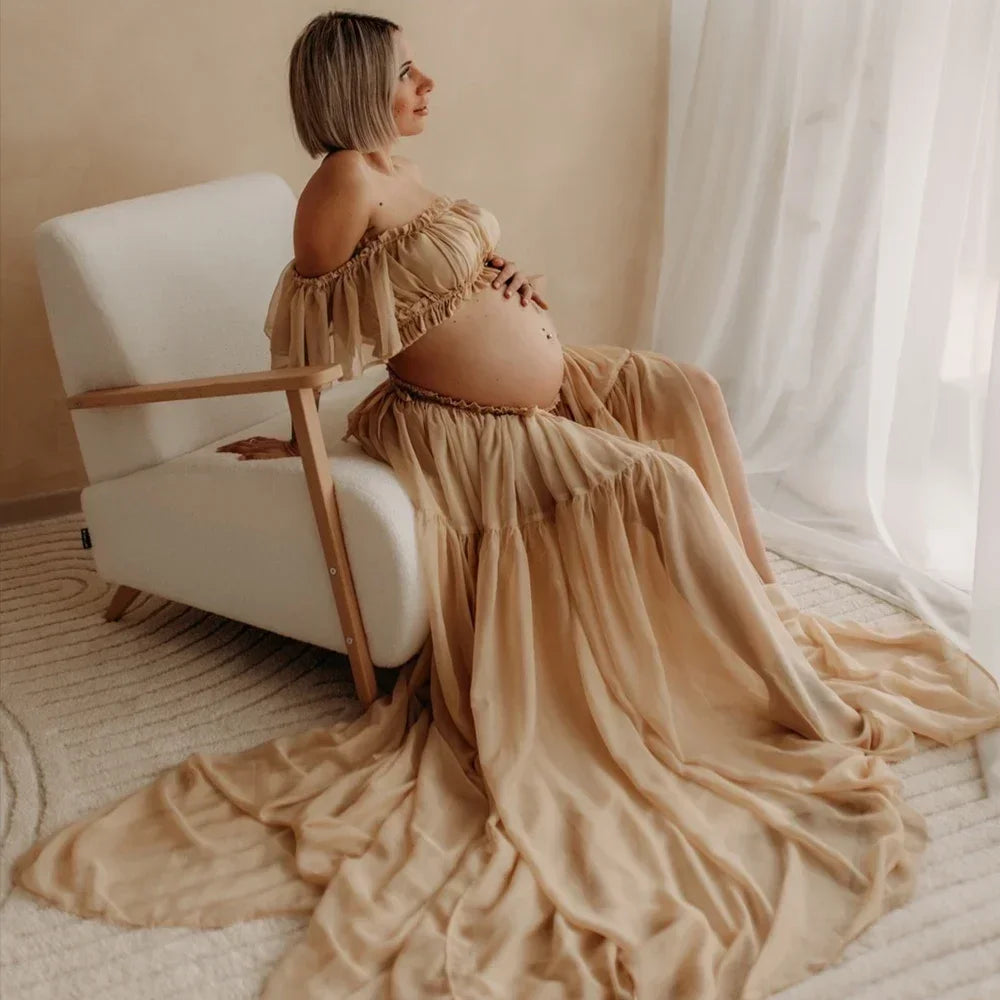 Pregnant woman in a boho two-piece maternity set seated on a chair, showcasing a natural color dress.