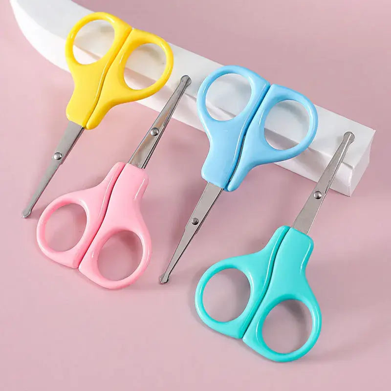 Colorful baby nail scissors in yellow, pink, blue, and green on a pink background, perfect for newborn hygiene.