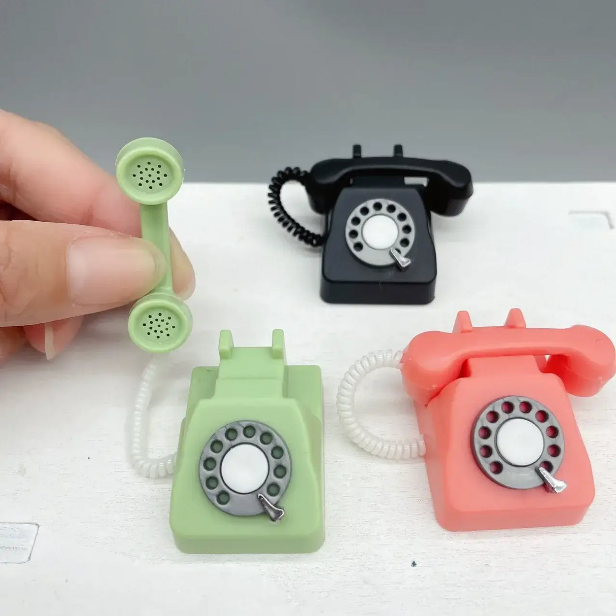 Colorful miniature telephones for photography props, featuring green, black, and coral designs, ideal for newborn photoshoots.