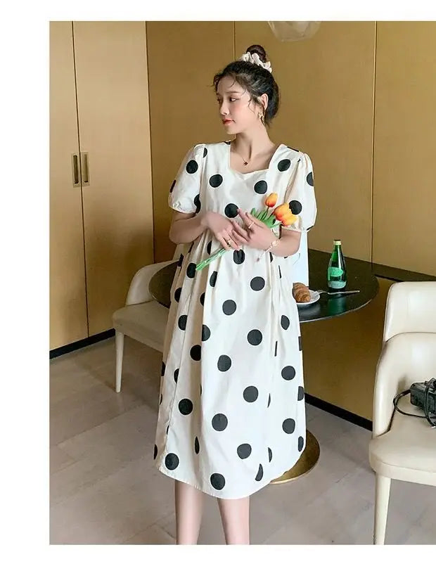 Polka dot loose maternity dress in a bright setting, perfect for summer, featuring short sleeves and a comfortable fit.