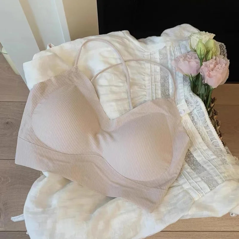 CrossForm™ Padded Backless Tank Top in soft beige resting on white fabric with flowers.