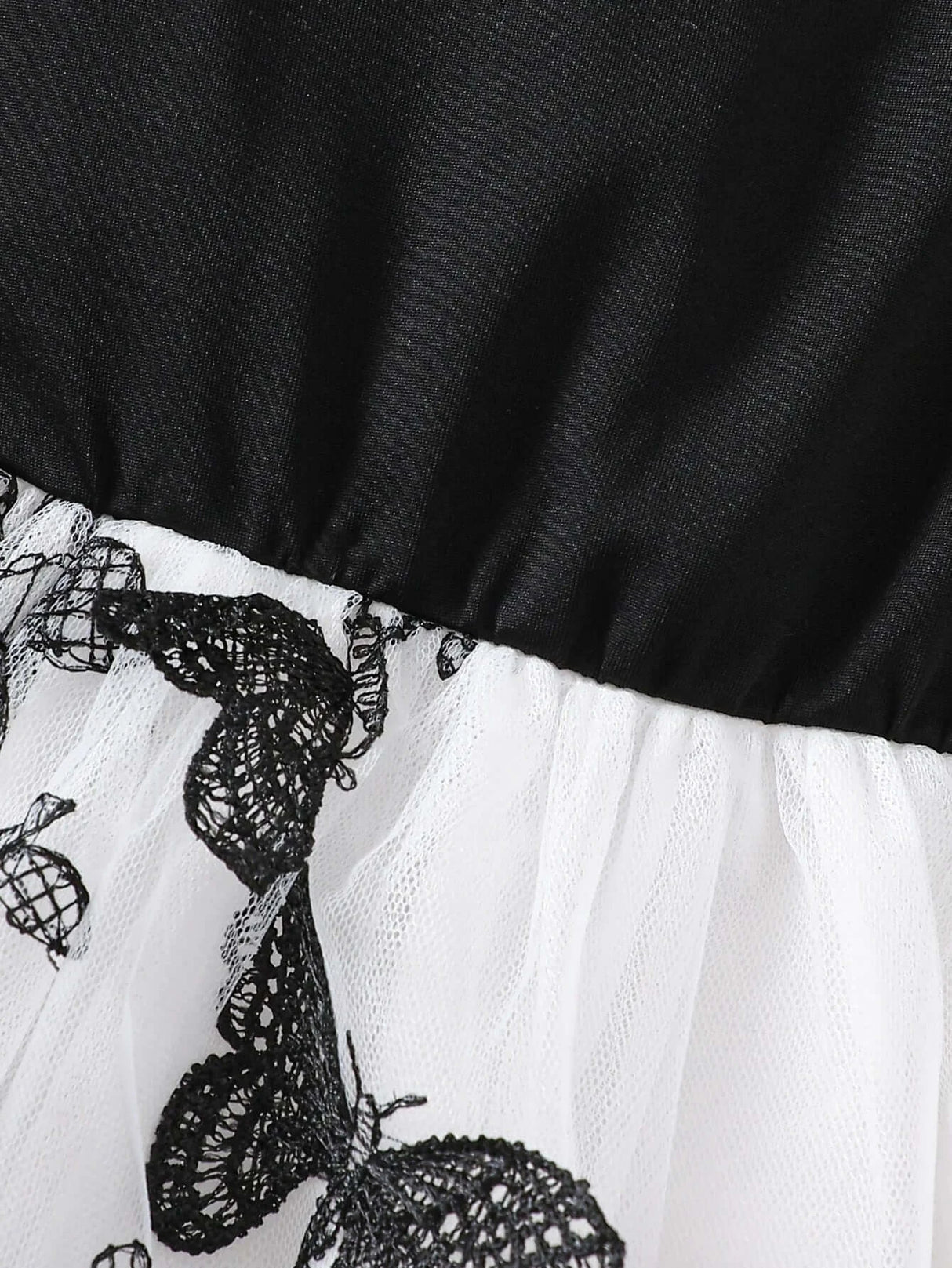 Close-up of toddler girl dress featuring lace butterfly detailing on tulle skirt and smooth satin bodice.