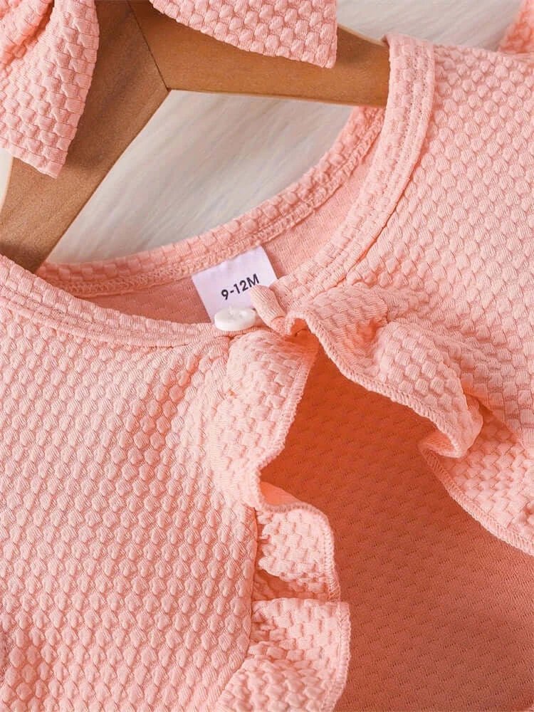 Close-up of a peach newborn girl dress with ruffles and a size tag, perfect for summer fashion.