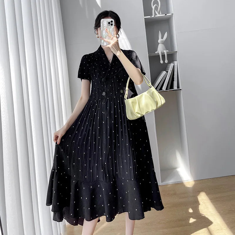 Black polka dot A-line maternity dress with short sleeves, V-neck, and flowing mid-calf length.