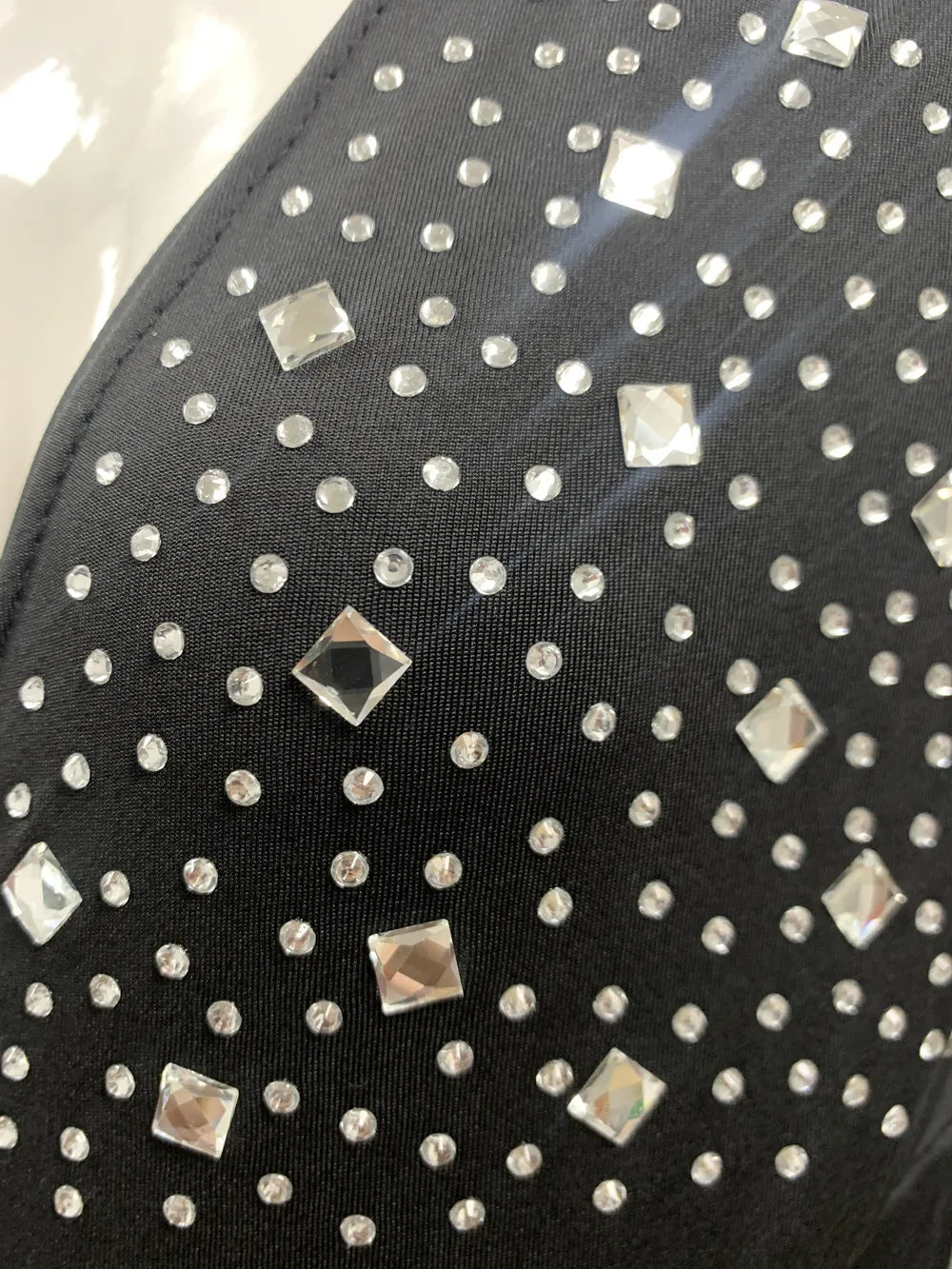 Close-up of shiny rhinestones and studs on black fabric, adding elegance to the maternity dress for summer events.