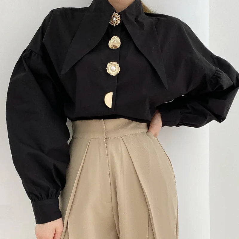 Chic black shirt with pearl-button detail, styled with cream trousers, showcasing Y2K fashion.