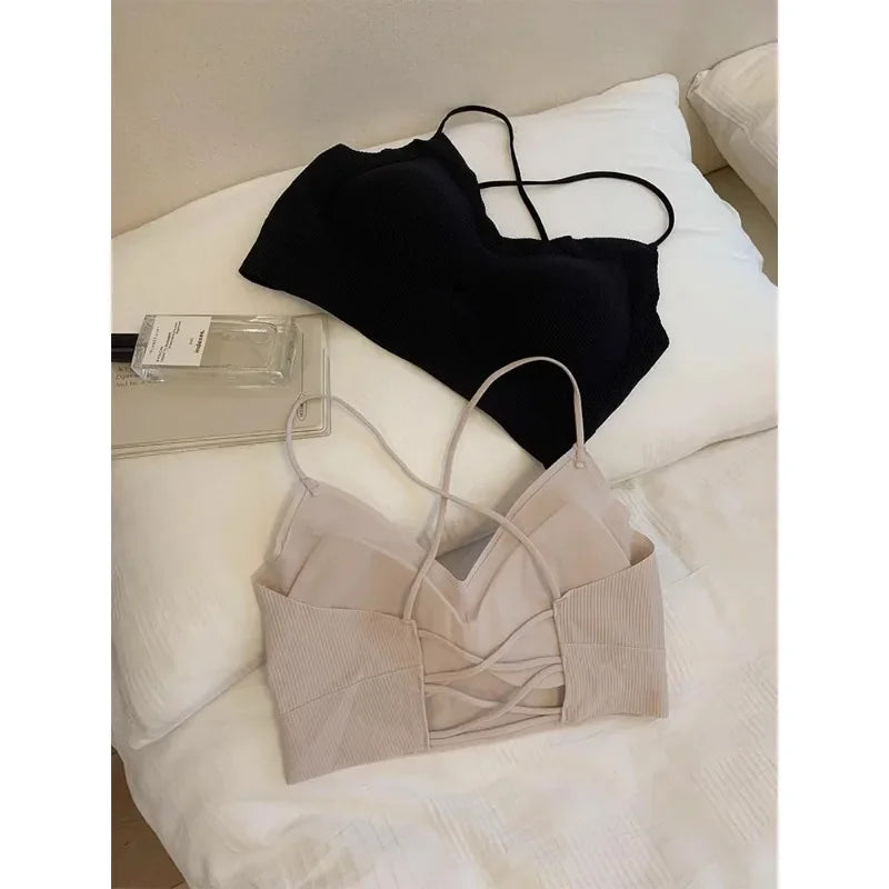 Black and beige padded backless tank tops displayed on a bed, featuring a stylish design for summer wear.