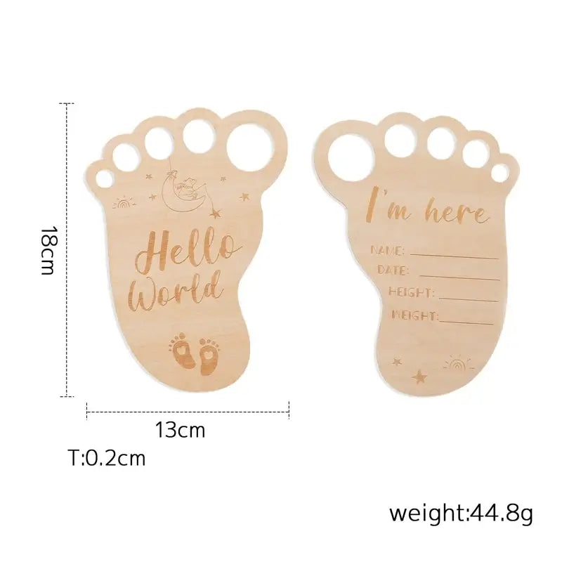 Wooden newborn milestone card in foot shape, engraved with 'Hello World' and space for baby's info.