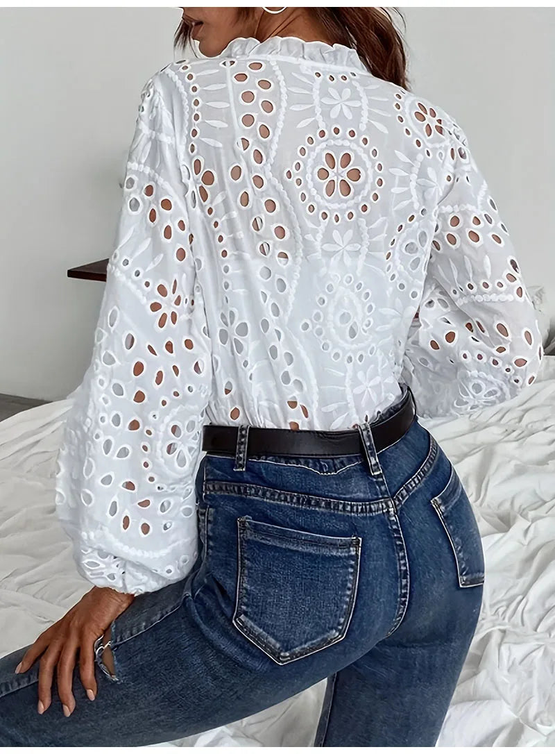 Back view of a woman wearing a hollow-out white lace shirt with long sleeves and jeans, showcasing elegant summer style.