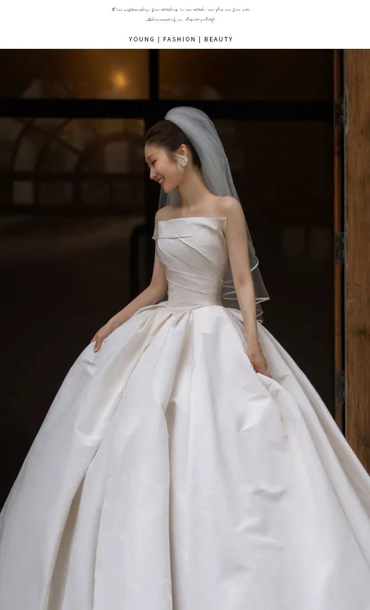 Elegant bride in a strapless white satin wedding dress, showcasing timeless beauty and fashion. Perfect for bridal occasions.