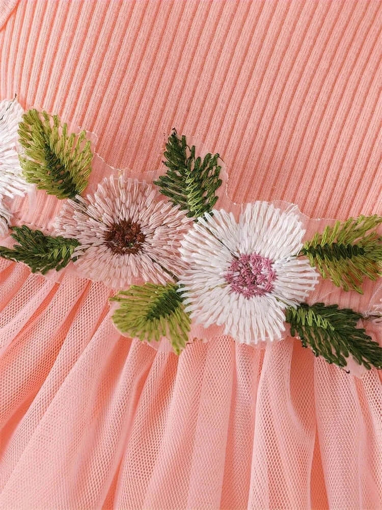 Close-up of peach dress for baby girls, featuring floral embroidery and delicate lace details ideal for summer.