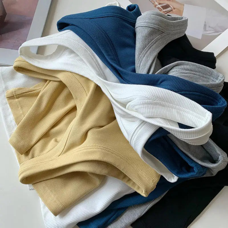 Colorful stack of SlimCotz™ padded cotton spaghetti camis in various hues, perfect for summer and breathable styling.