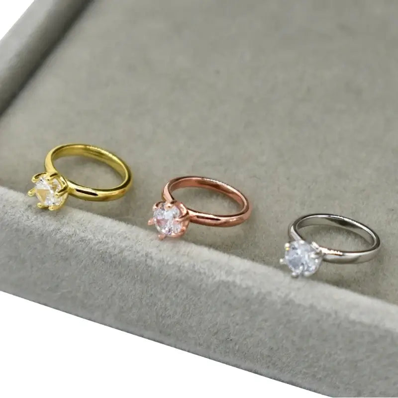 Three exquisite newborn baby angel rings in gold, rose gold, and silver settings, featuring sparkling gemstones.