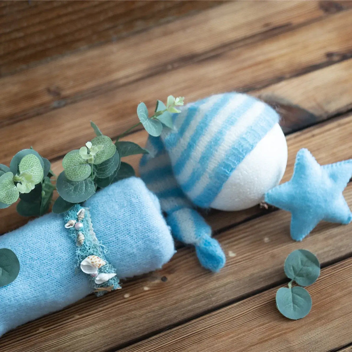 Soft blue newborn stretch knit mohair with a striped hat and decorative star on a rustic wooden background.