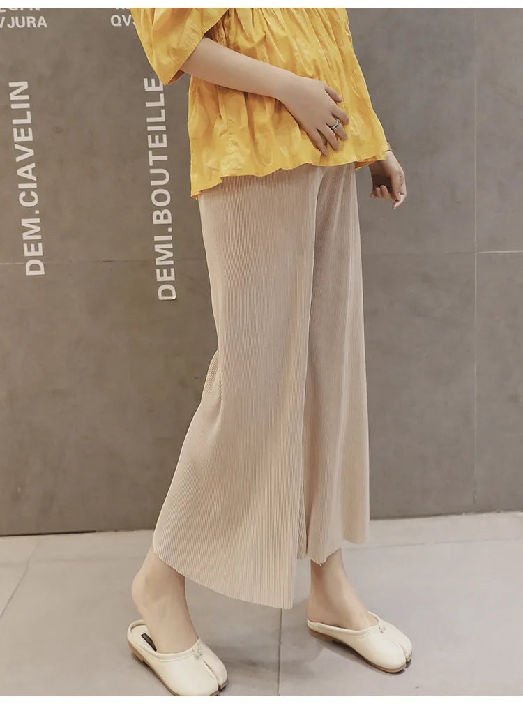 Model wearing Ice Silk Pleated Maternity Pants in beige, paired with a yellow top, showcasing summer style and comfort.
