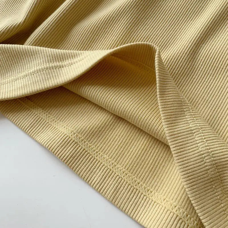 Close-up of the fabric texture of a slim fit padded cotton spaghetti camisole in soft yellow color.