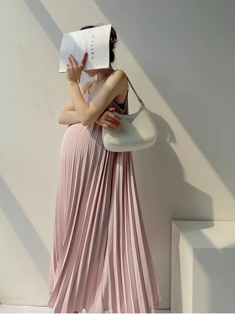 Pleated chiffon maternity dress in soft pink, mid-calf length, complementing a pregnant woman's silhouette.