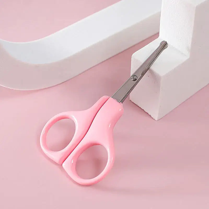 Pink baby nail scissors on a light pink background, ideal for newborn care and nail trimming.