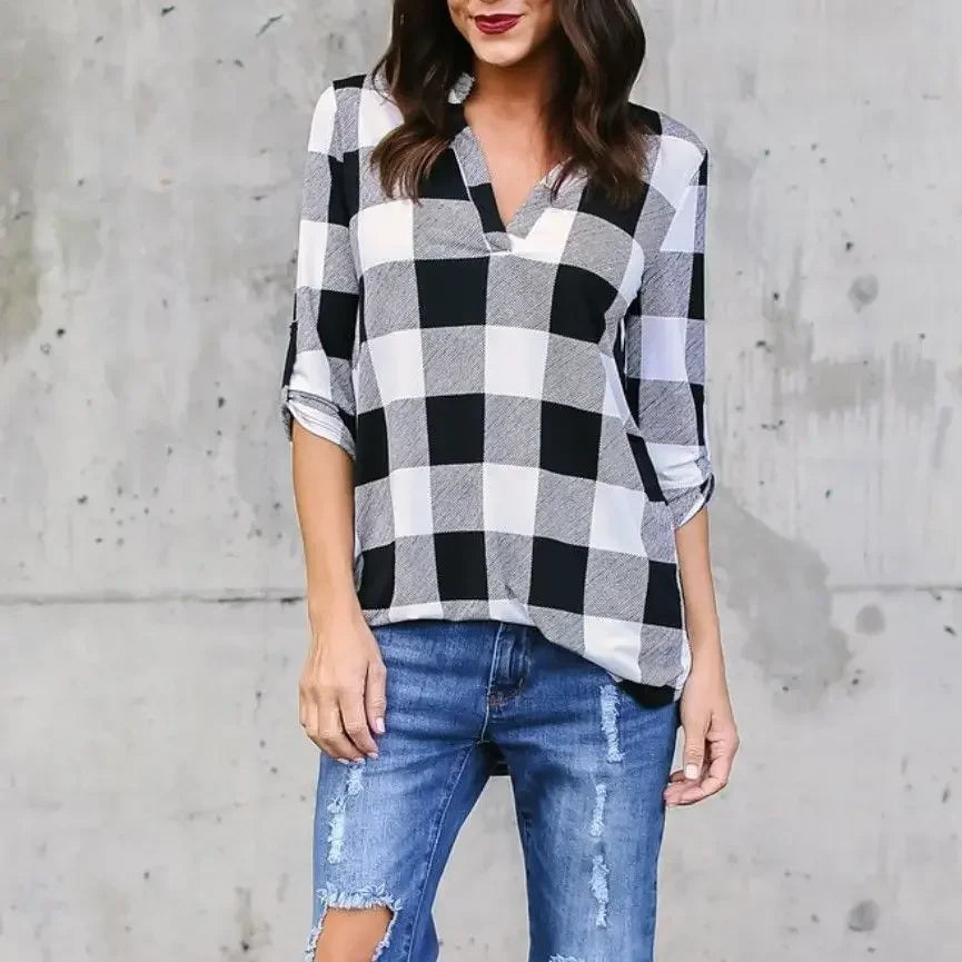 Woman in a black and white plaid V-neck summer t-shirt paired with ripped jeans, showcasing casual beach style.