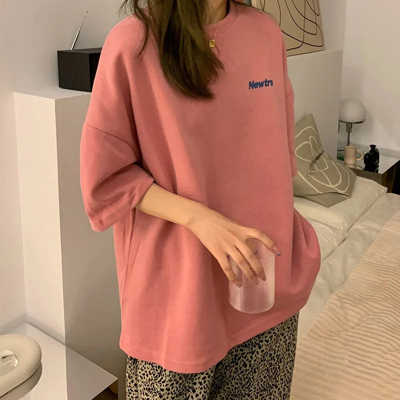 Oversized Harajuku streetwear tee in pink, featuring 'Newtro' text, styled with loose fit and comfortable fabric.