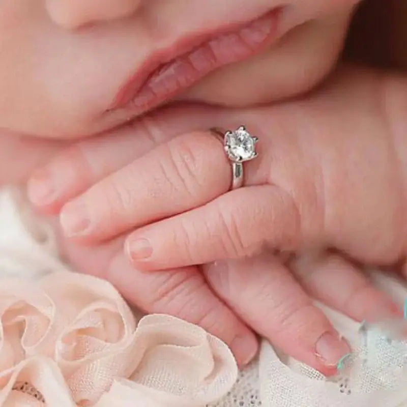 Newborn baby with a delicate angel ring, showcasing a sparkling gem, perfect for ages 0-6 months, by THINKTHENDOG.