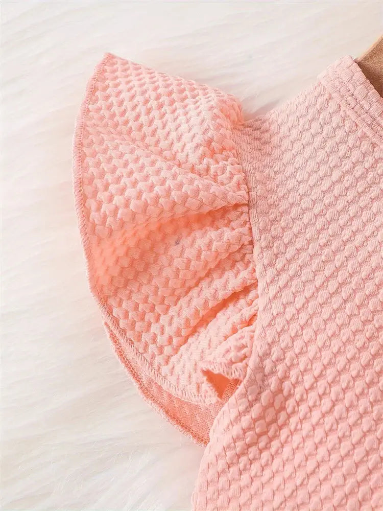 Close-up of the pink short-sleeve ruffled detailing on a newborn baby girl's dress, made from soft cotton.