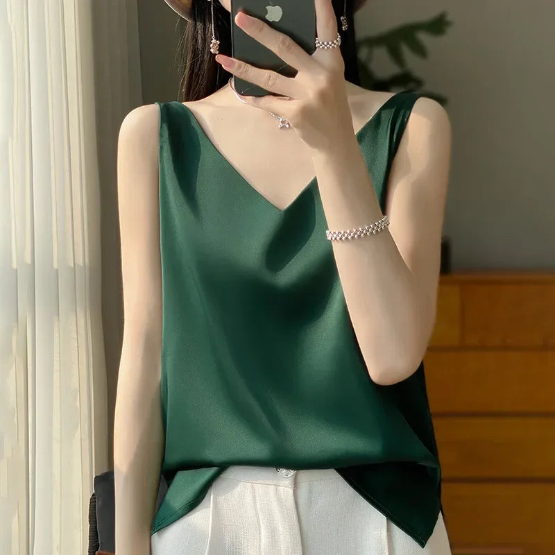 Model wearing a green satin V-neck camisole, showcasing summer style and elegance in casual indoor setting.
