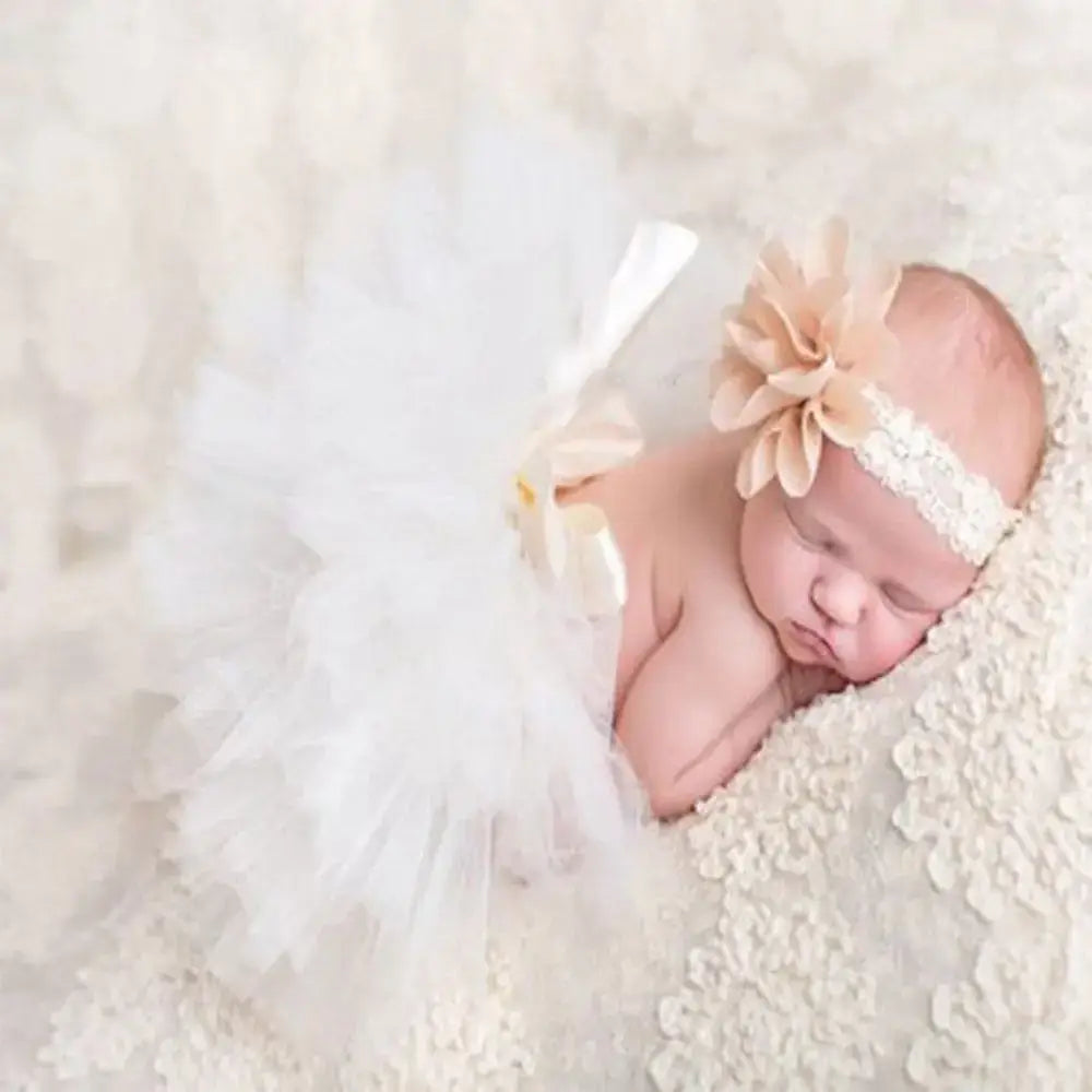Newborn girl in a white infant tutu skirt and floral headband, perfect for photography and baby photoshoots.
