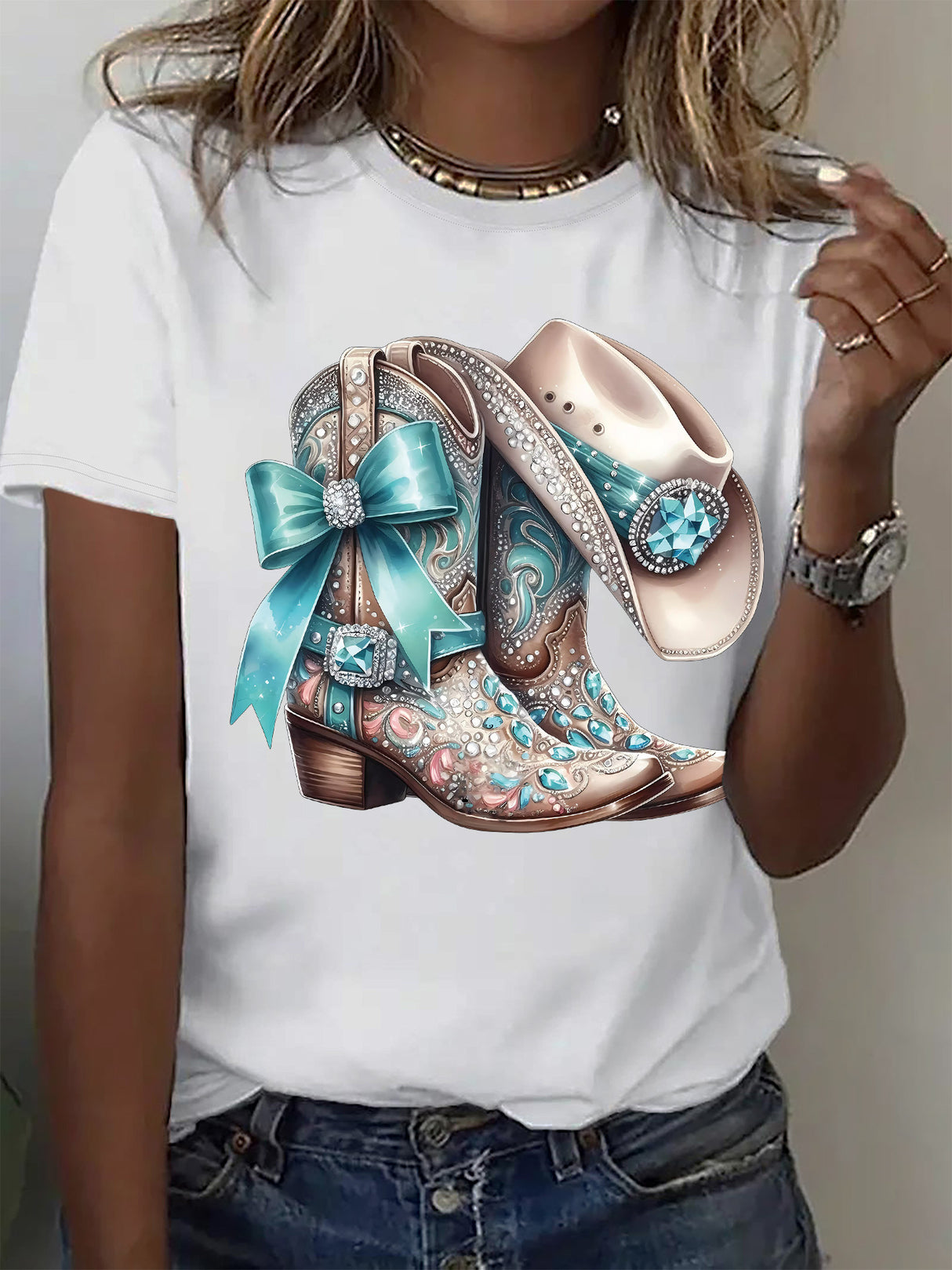 Stylish woman wearing a white crew neck t-shirt featuring decorative cowboy boots and a hat with turquoise accents.