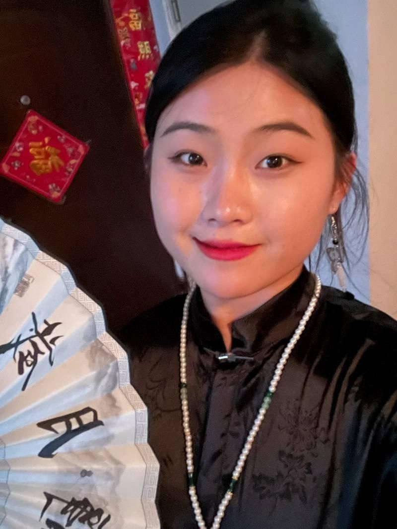 Woman wearing traditional Hanfu outfit, holding a decorative fan, showcasing cultural attire with elegance.