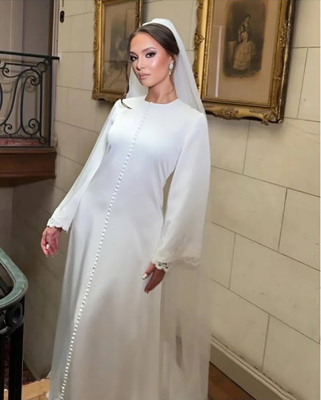 Elegant bride in a long-sleeve white gown with buttons and veil, showcasing timeless bridal beauty.