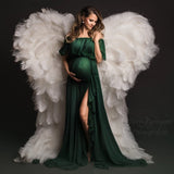 Maternity model in a green chiffon ruffle sleeve dress with angel wings backdrop, showcasing summer elegance.