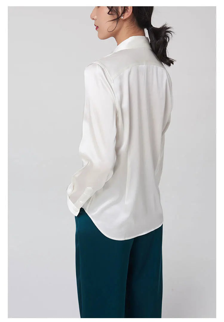 Back view of a woman wearing a loose fit, long sleeve silk shirt in white, showcasing premium Mulberry silk fabric.