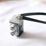Miniature black dollhouse camera with a strap labeled 'Rock n Roll', ideal for baby photography props.