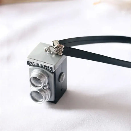 Miniature black dollhouse camera with a strap labeled 'Rock n Roll', ideal for baby photography props.