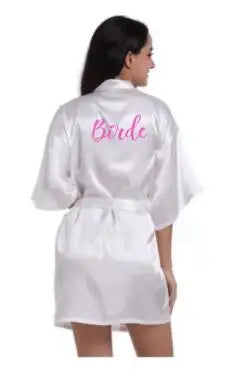 Model wearing a back view of a white satin robe with 'Bride' written in pink, perfect for bridal sleepwear.