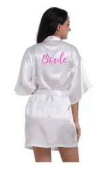 Back view of a woman wearing a satin robe with the word 'Bride' in pink, ideal for wedding celebrations.