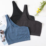 Three colors of MonoSculpt™ One-Shoulder Seamless Crop Tops displayed with a magazine and flowers.