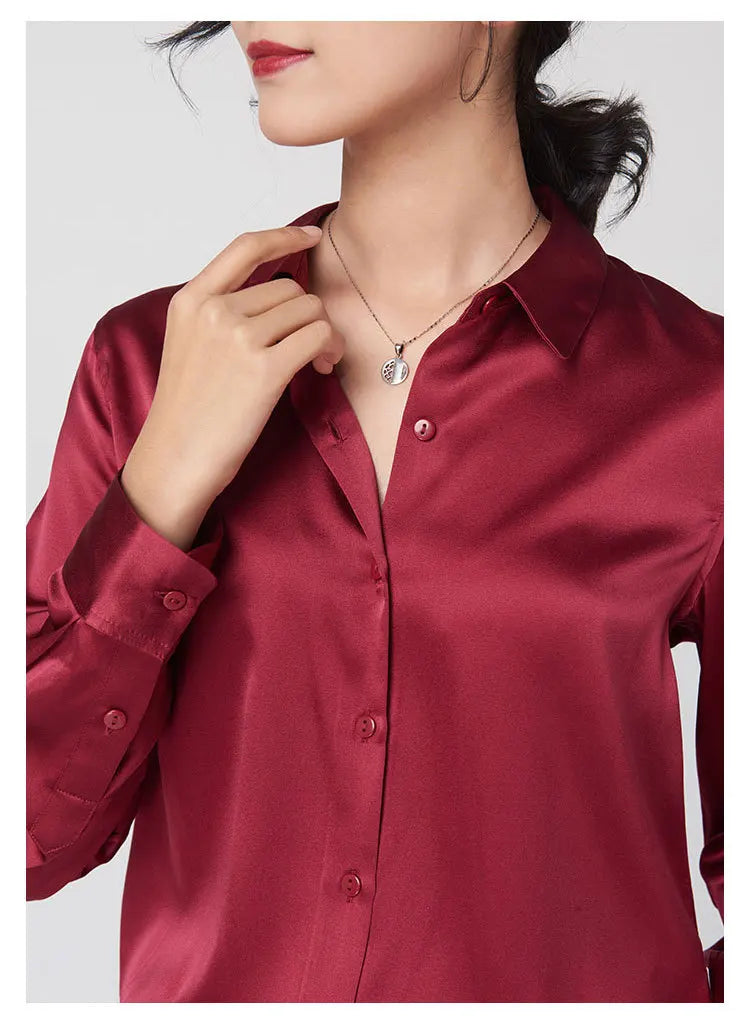 Close-up of a woman wearing a burgundy SatinGrace™ long sleeve silk shirt with a V-neck and necklace detail.
