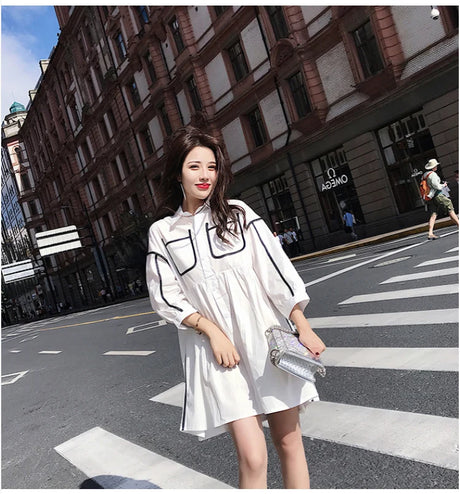 Woman wearing a solid color maternity shirt dress with pockets, styled for a summer beach party.