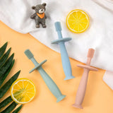 Colorful soft silicone training toothbrushes for babies with a cute bear toy and lemon slices on a bright background.