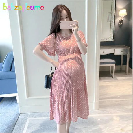 Chiffon polka dot maternity dress in pink worn by pregnant woman, showcasing casual summer style.