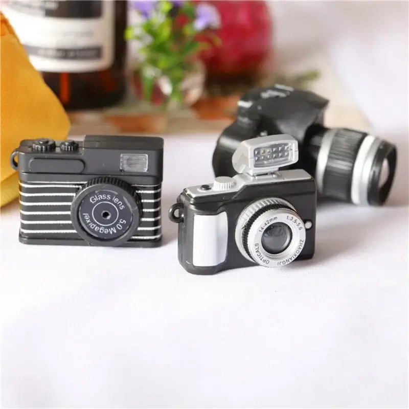 Miniature black camera toys for dollhouse photography props, ideal for baby photo sessions.