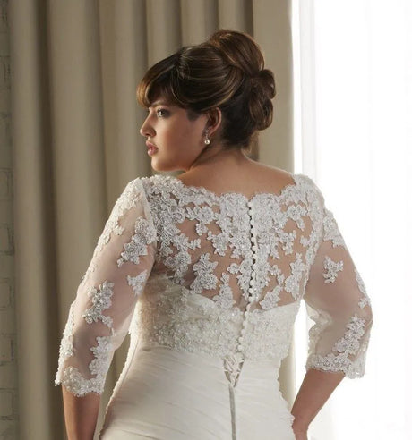 Elegant bride showcasing a crystal beaded wedding jacket with 3/4 sleeve bolero, featuring intricate lace appliqué details.