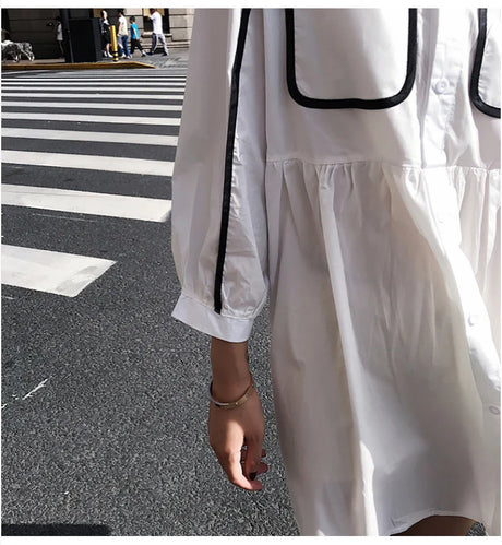 Close-up of a woman's hand holding a solid color maternity shirt dress with pockets, perfect for summer beach parties.