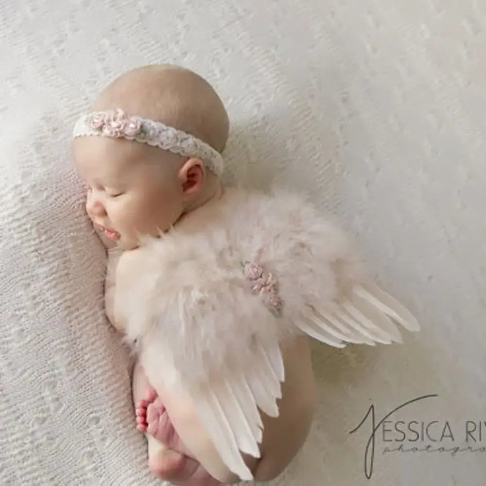 Adorable newborn wearing angel feather wings and a rose flower headband, perfect for baby photos and props.